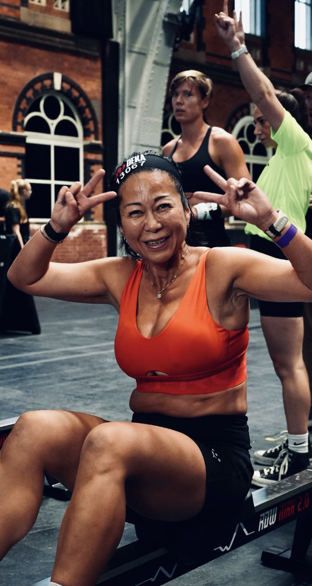 Line smiling and flashing peace signs on a rowing machine at a DEKA race